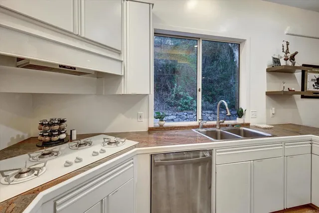 a kitchen with sink a stove and white cabinets