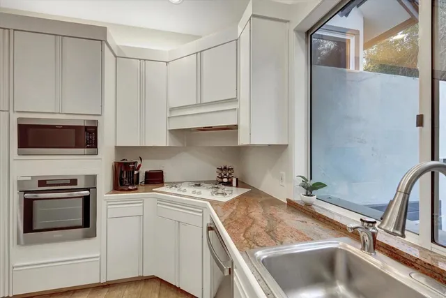 a kitchen with granite countertop a sink stainless steel appliances and cabinets