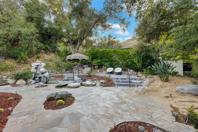 a backyard of a house with table and chairs under an umbrella
