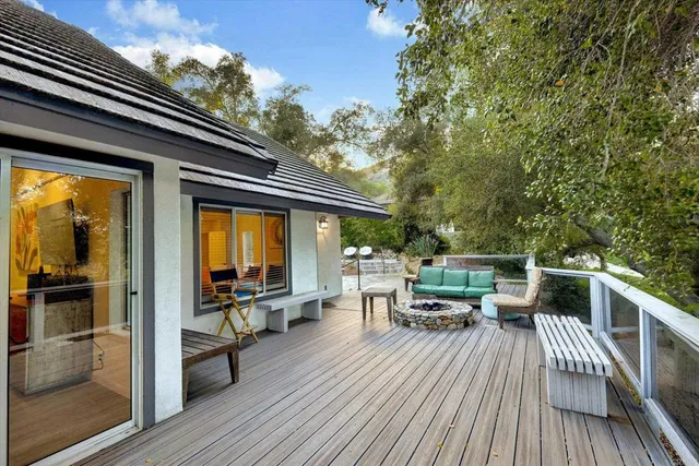 a view of a patio with couches table and chairs and potted plants with wooden floor and fence