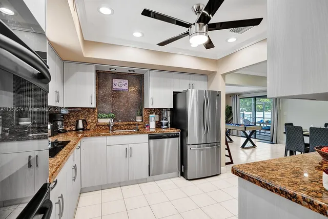 a kitchen with granite countertop a refrigerator a sink a stove top oven and cabinets