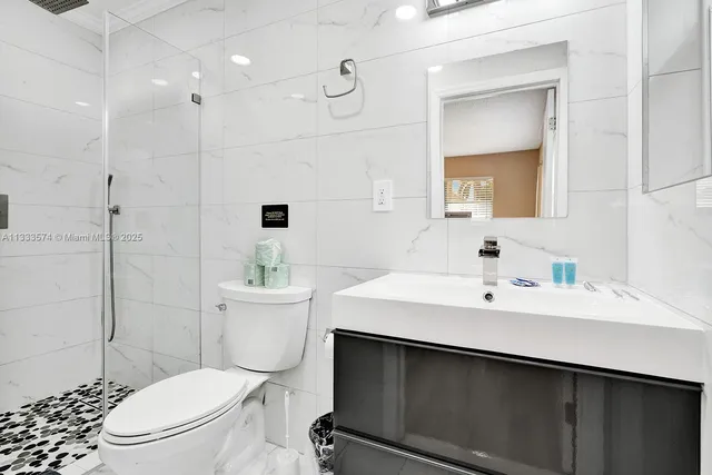 a bathroom with a sink a toilet a mirror and shower