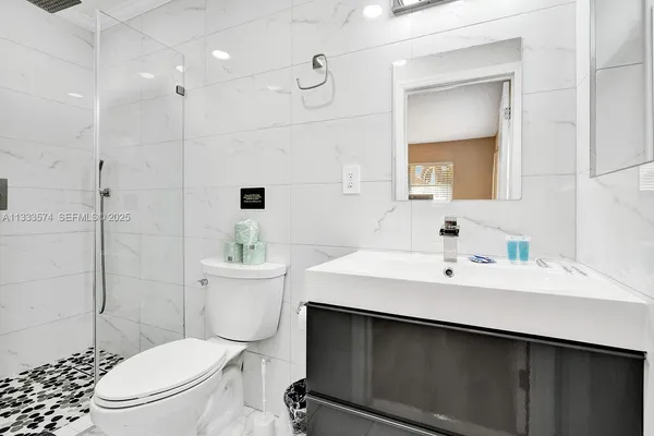 a bathroom with a sink a toilet a mirror and shower