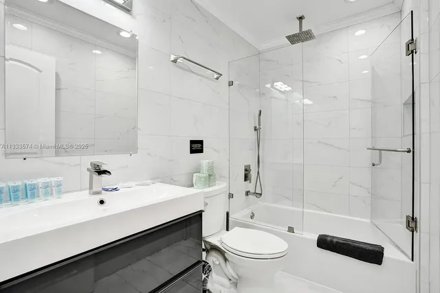 a bathroom with a sink a toilet a mirror and shower