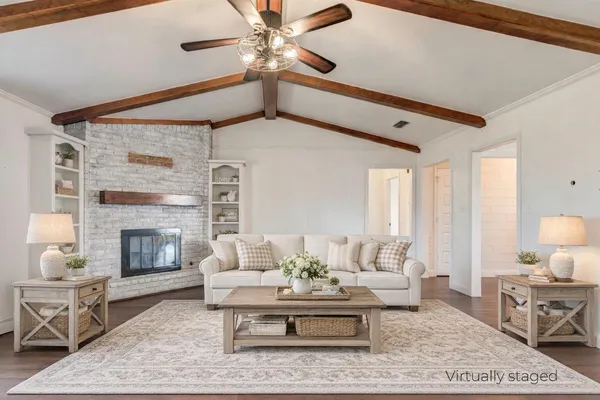 a view of an empty room with wooden floor fireplace and a window