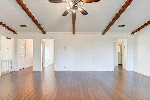 a kitchen with stainless steel appliances granite countertop a refrigerator a sink dishwasher a oven a dining table and chairs with wooden floor