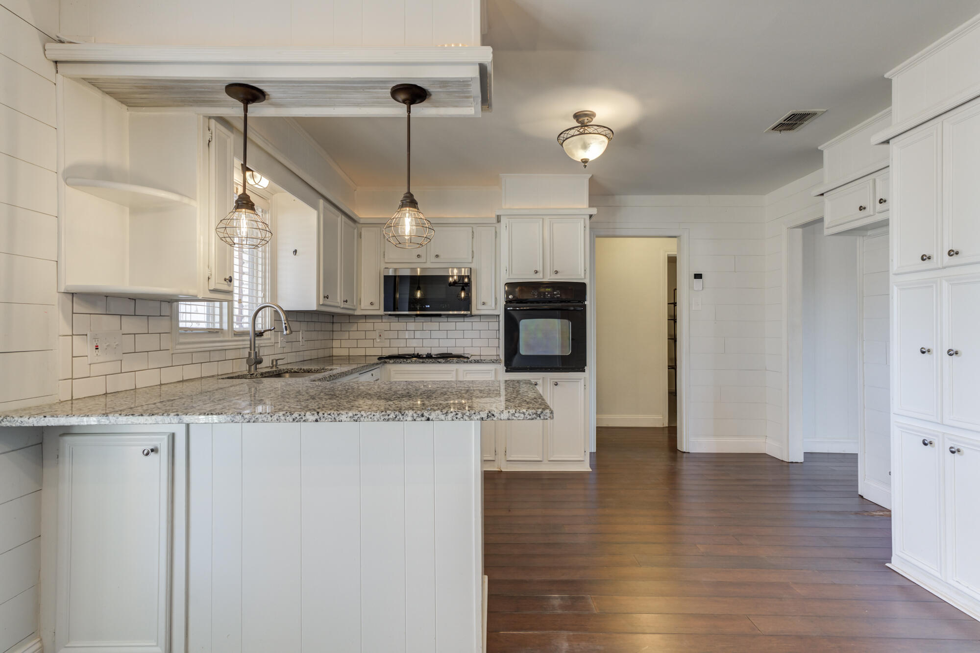 5604 70th Street Lubbock, TX 79424 - Photo 32 of 49 a kitchen with stainless steel appliances granite countertop a refrigerator a sink dishwasher a oven a dining table and chairs with wooden floor