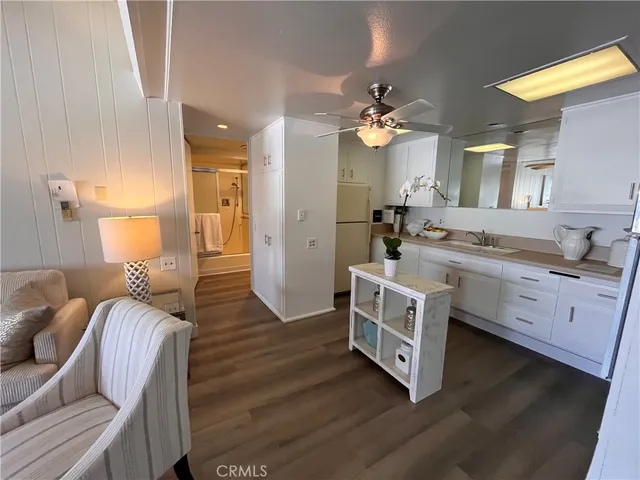 a large white kitchen with a stove a sink dishwasher and a fireplace with wooden floor