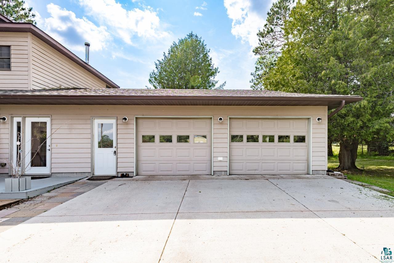 4800 Tower Road Moose Lake, MN 55767 - Photo 25 of 83 Exterior featuring a two-car garage with panel doors and upper window inserts, a concrete driveway, and light tan siding