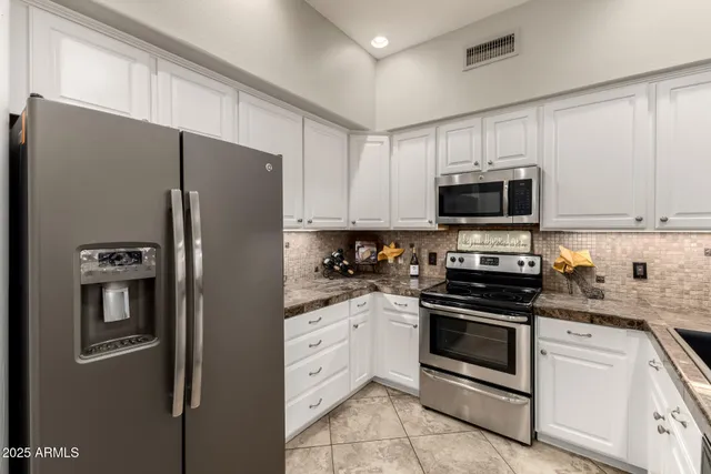 a kitchen with stainless steel appliances white cabinets and refrigerator