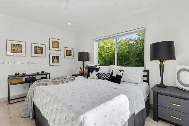 a bedroom with a bed and a lamp on dresser next to a window