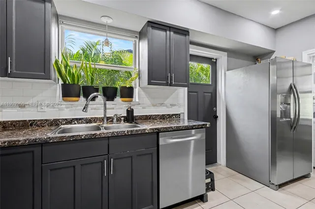a kitchen with stainless steel appliances granite countertop a sink and a refrigerator