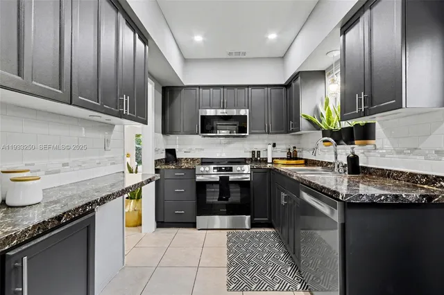 a kitchen with stainless steel appliances granite countertop a stove sink microwave and cabinets