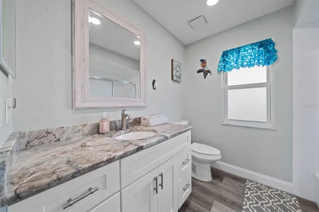 a bathroom with a granite countertop sink a toilet and a mirror
