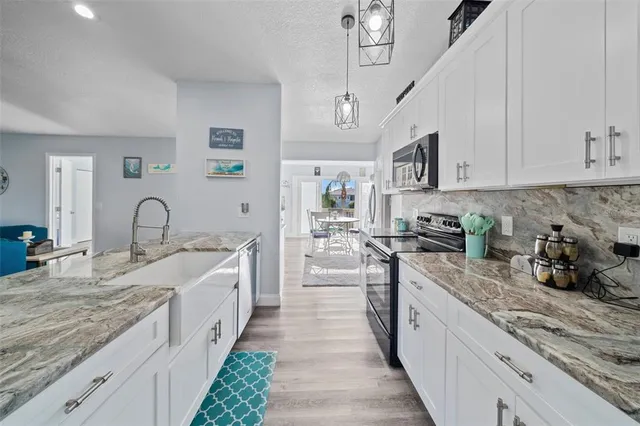 a kitchen with kitchen island granite countertop a sink stainless steel appliances and white cabinets