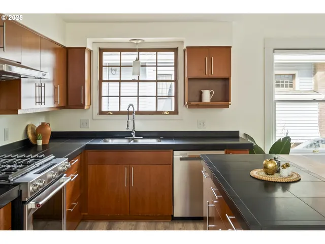 a kitchen with a sink a stove cabinets and a window