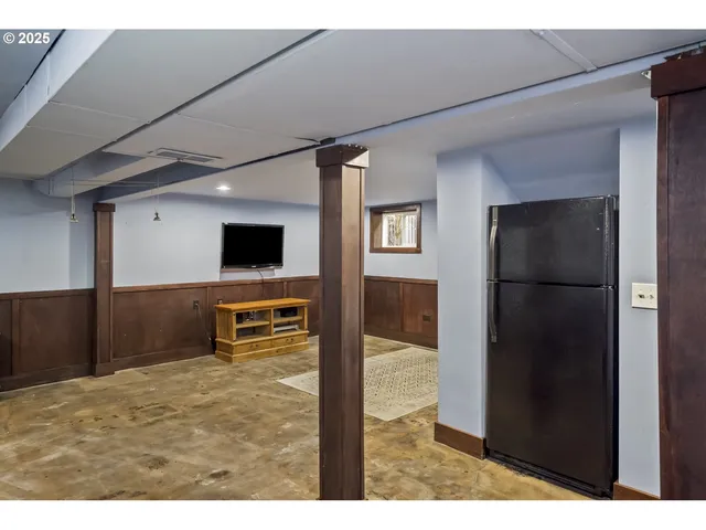 a living room with stainless steel appliances kitchen island granite countertop a refrigerator and a flat screen tv