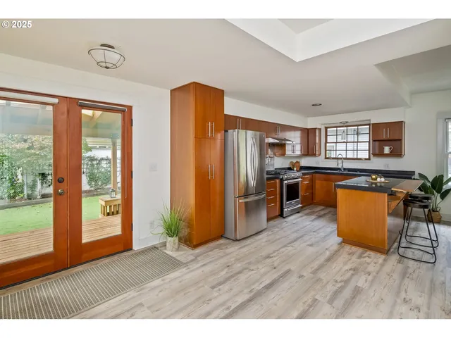 a view of kitchen with stainless steel appliances granite countertop a refrigerator a sink a stove and wooden floors