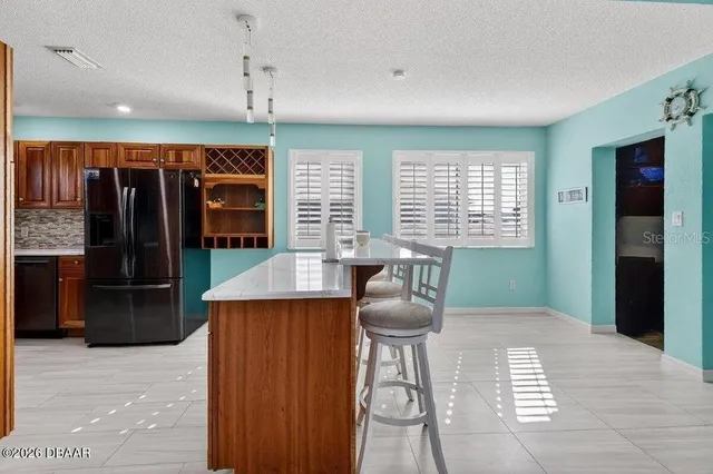 a kitchen with stainless steel appliances kitchen island granite countertop a refrigerator a sink and dishwasher