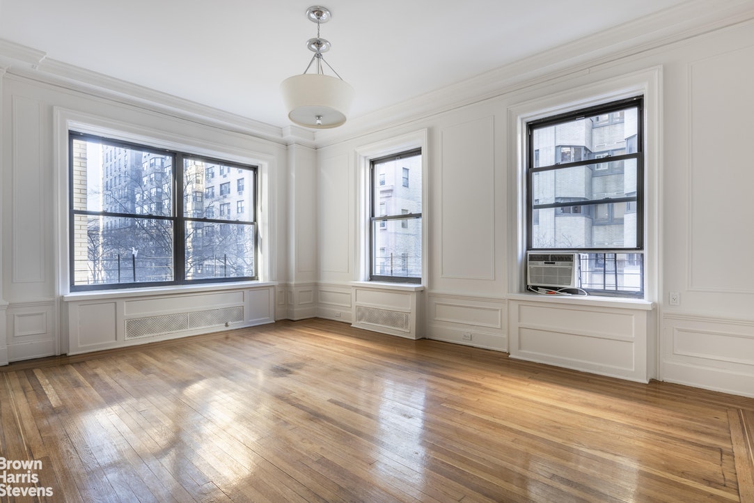 a view of an empty room with a window and wooden floor
