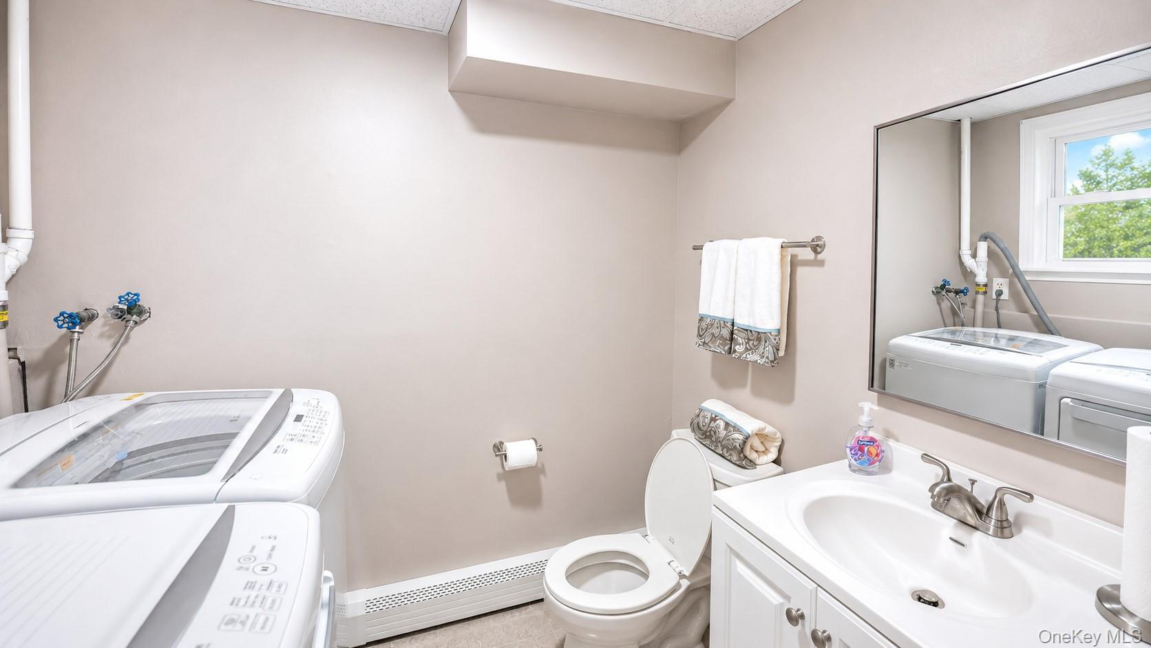 60 Sutton Park Road Poughkeepsie, NY 12603 - Photo 22 of 30 White vanity with a basin sink and brushed nickel faucet, large wall mirror, and a window