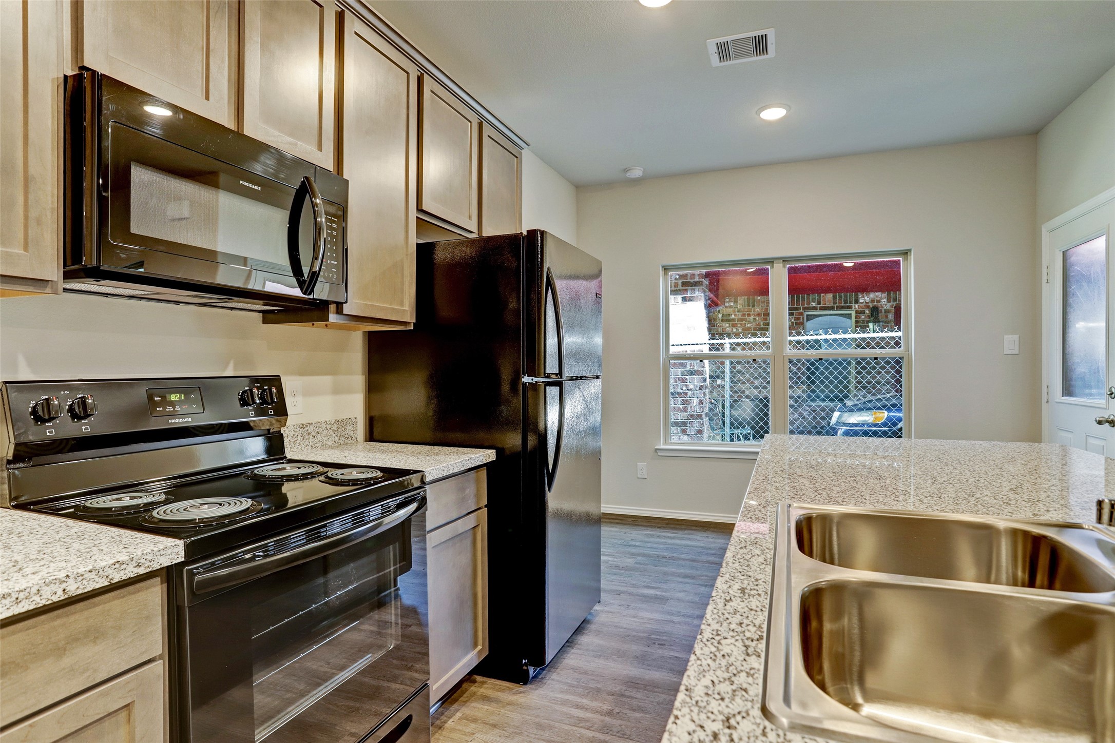 409 South 12th Street, Unit B Conroe, TX 77301 - Photo 6 of 14 This kitchen features modern appliances, granite countertops, and ample cabinetry. It has a double sink, a large window for natural light, and a sleek, open layout.