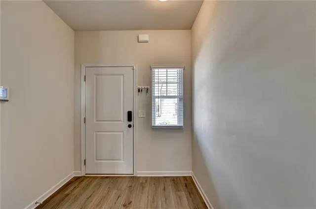 a view of an empty room with wooden floor and a window