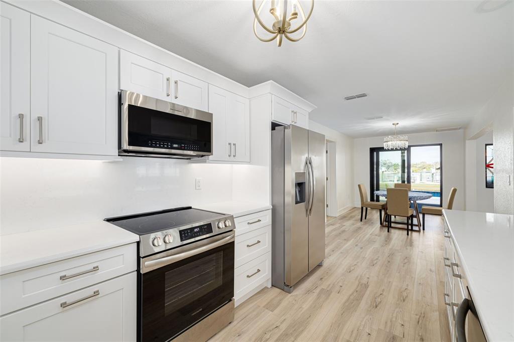 5531 Manatee Point Drive New Port Richey, FL 34652 - Photo 8 of 61 a kitchen with stainless steel appliances a white stove top oven a chimney cabinets and a wooden floor