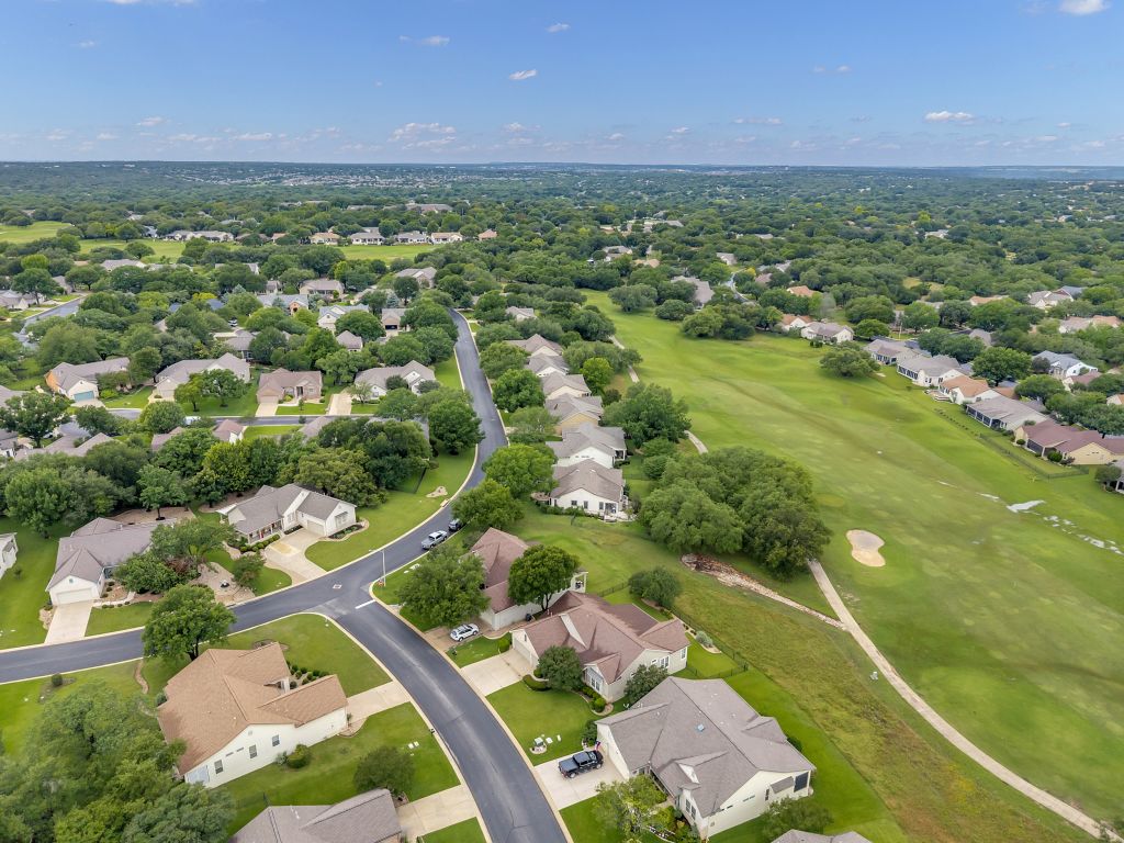 144 Cattle Trail Way Georgetown, TX 78633 - Photo 33 of 37 An aerial perspective reveals a harmonious community nestled amidst lush green spaces and a pristine golf course.