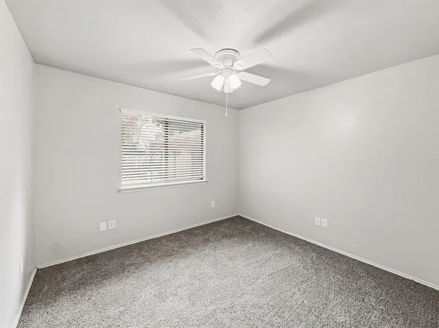 an empty room with a window and a fan