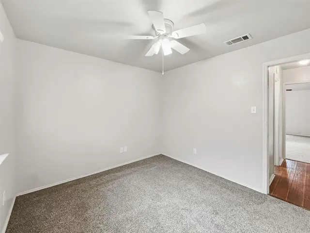 an empty room with a chandelier fan and windows