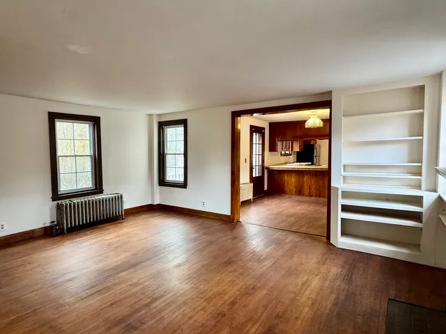 an empty room with wooden floor closet and windows