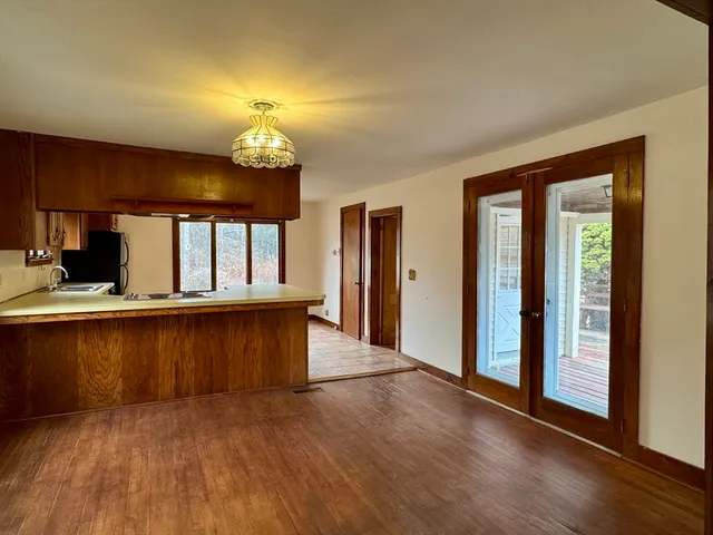 an empty room with wooden floor chandelier and windows
