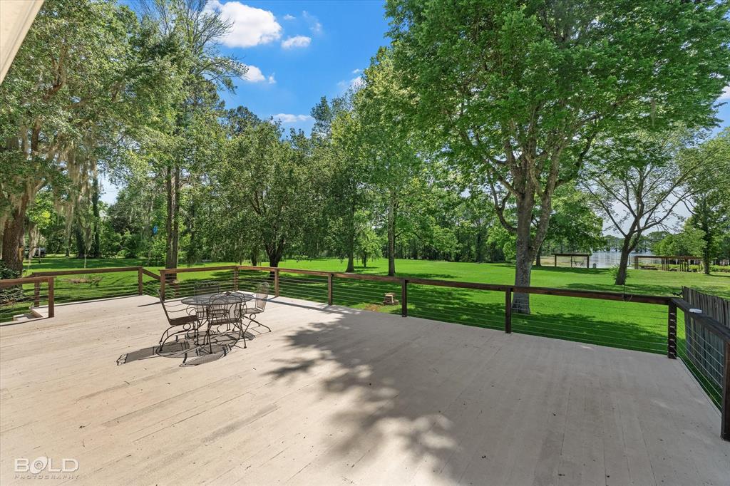 225 Marie Road Ringgold, LA 71068 - Photo 16 of 40 Spacious outdoor deck with cable railing overlooking a large grassy area and mature trees