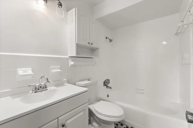 an empty room with wooden floor a ceiling fan and windows