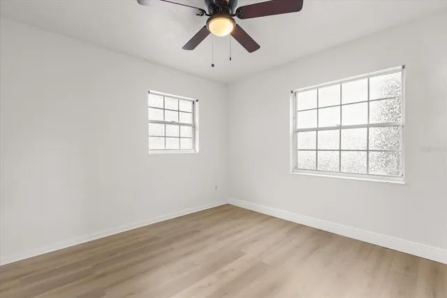 an empty room with chandelier fan and windows