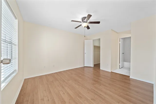 a view of empty room with wooden floor and fan