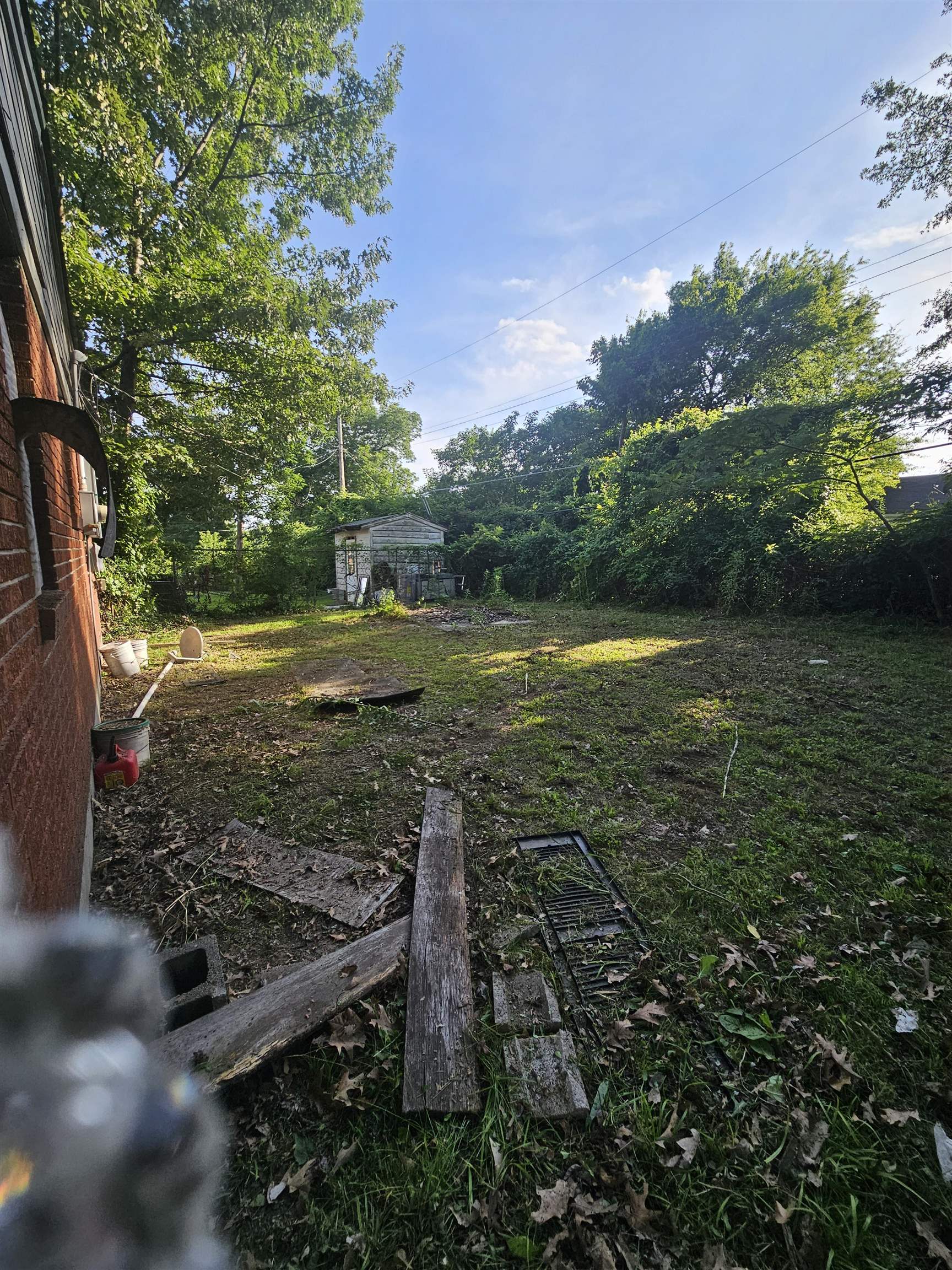 2059 Swift Street Memphis, TN 38109 - Photo 12 of 12 Expansive backyard area featuring a detached storage structure, mature trees, and a brick exterior wall