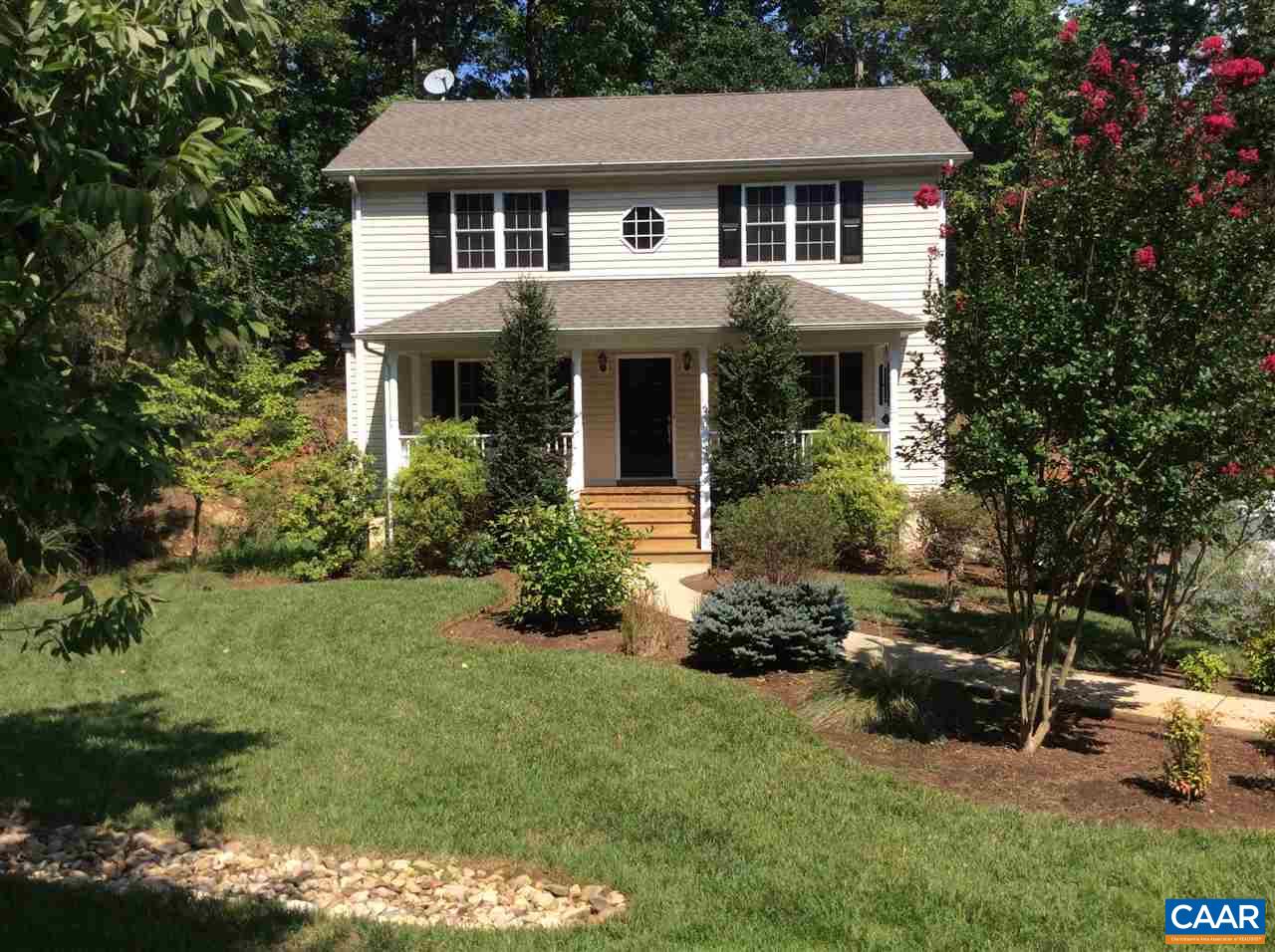a front view of a house with a garden and trees