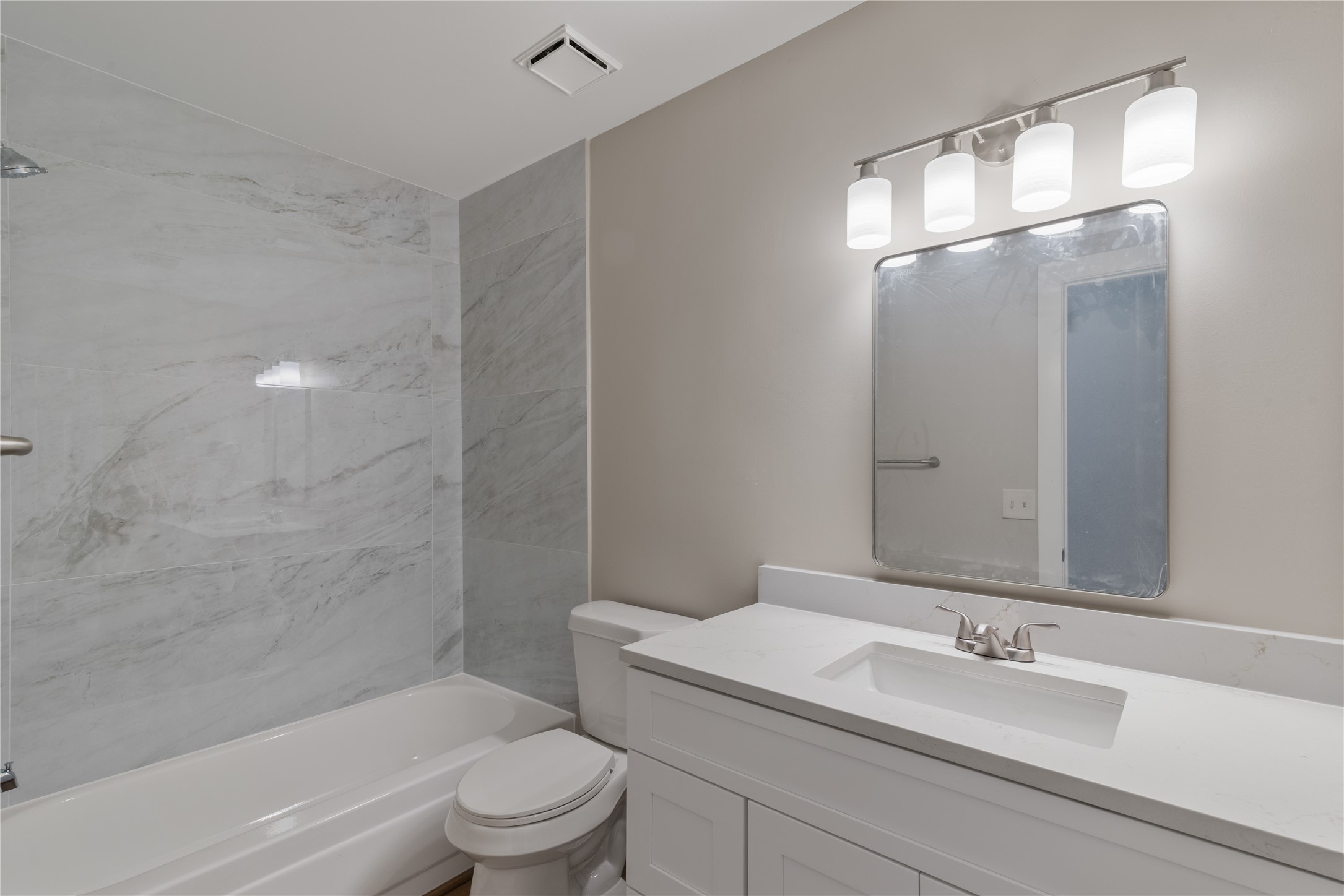 10 White Fawn Drive Spring, TX 77381 - Photo 11 of 25 This secondary bathroom features a sleek design with a large vanity, modern fixtures, and a spacious mirror. The shower area has elegant marble-style tiles, and overhead lighting provides a bright, inviting atmosphere.