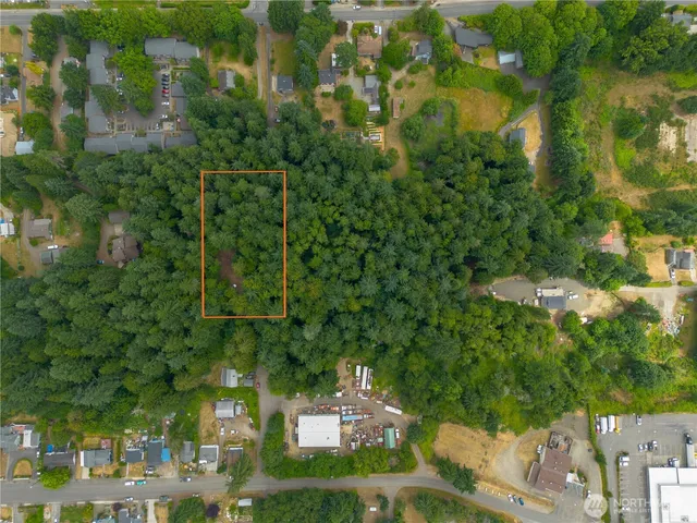 an aerial view of a residential houses with outdoor space and trees all around