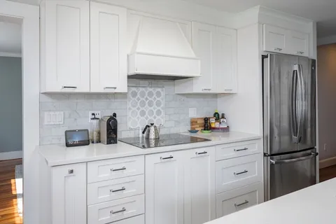a kitchen with white cabinets and refrigerator