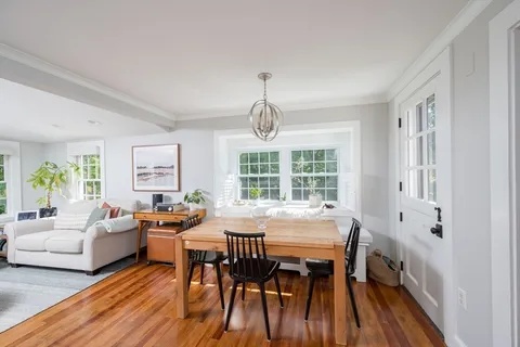 a dining room with wooden floor a chandelier a wooden table and chairs