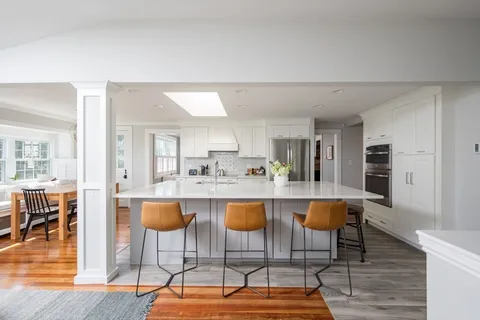 a dining hall with stainless steel appliances kitchen island granite countertop a dining table and chairs