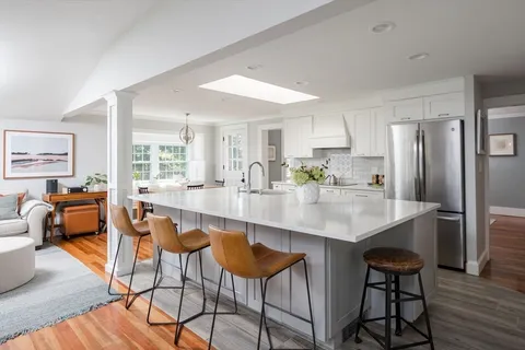 a kitchen with stainless steel appliances a dining table chairs and wooden floor