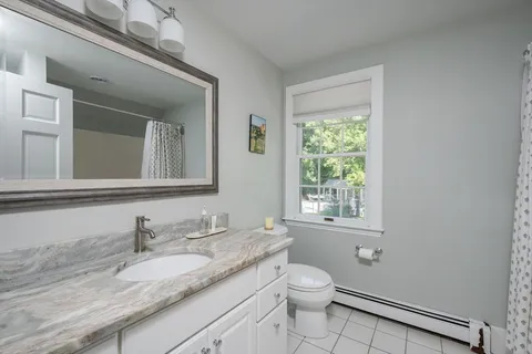 a bathroom with a granite countertop sink toilet a large mirror and a window