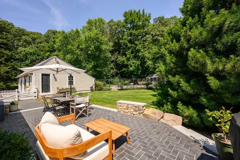 a view of a white house with a yard patio and a garden