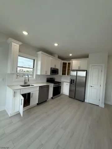 a large kitchen with cabinets wooden floor and stainless steel appliances