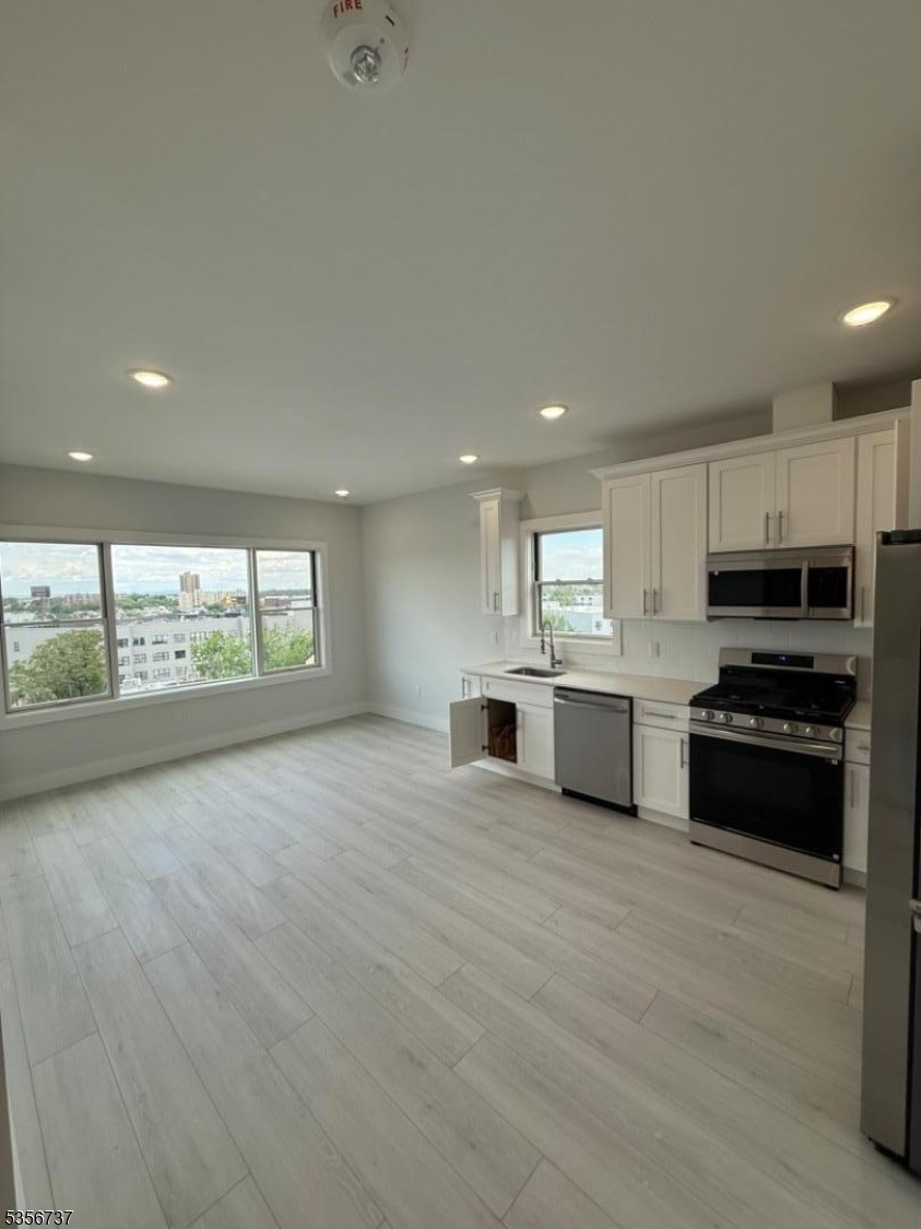 261 Marshall Street, Unit 504 Paterson, NJ 07503 - Photo 3 of 7 a large kitchen with stainless steel appliances granite countertop a stove a sink and a microwave