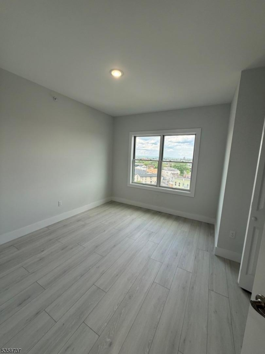 261 Marshall Street, Unit 504 Paterson, NJ 07503 - Photo 6 of 7 an empty room with wooden floor and windows